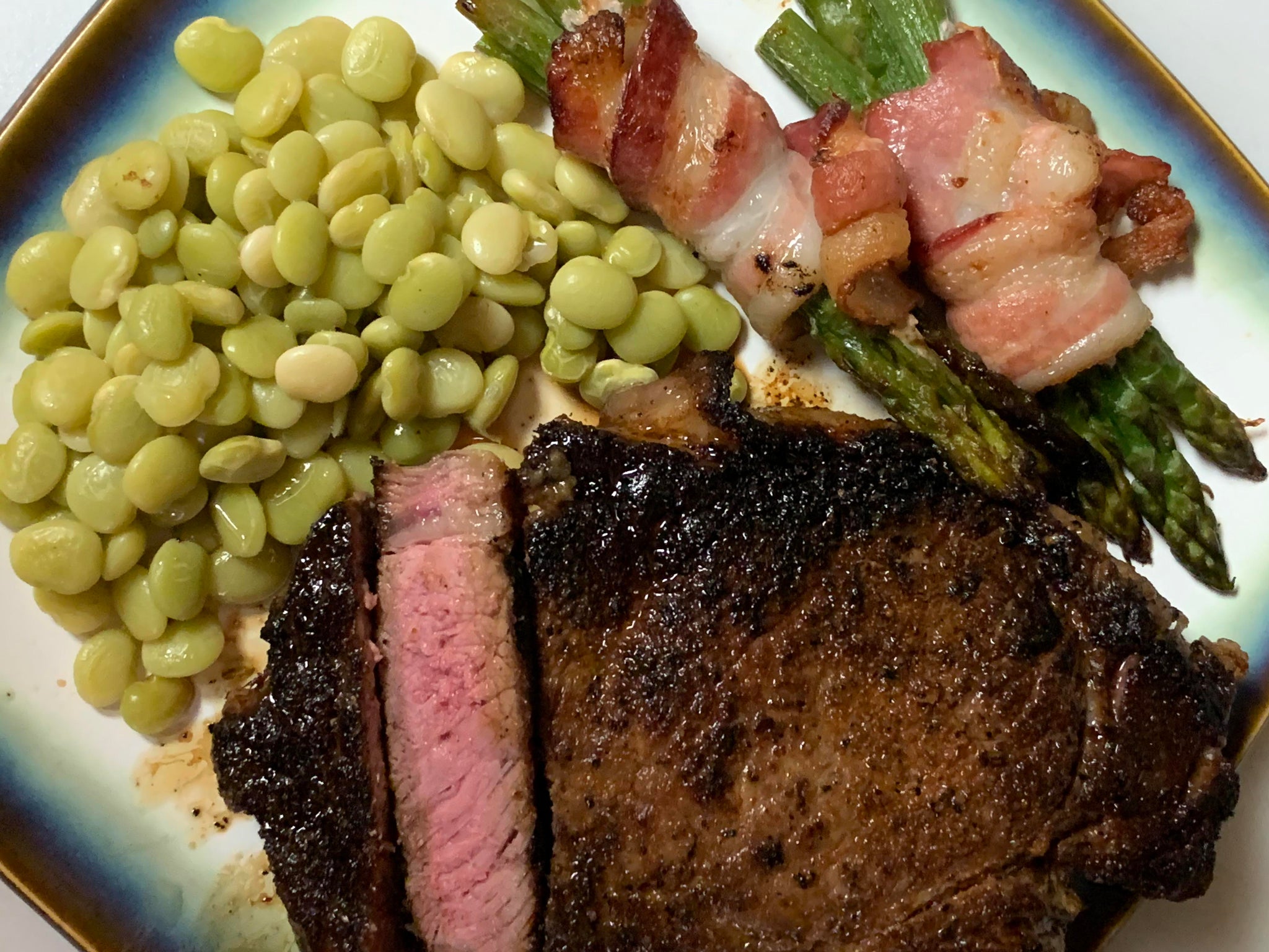 Ribeye steak with bacon wrapped asparagus and baby Lima beans